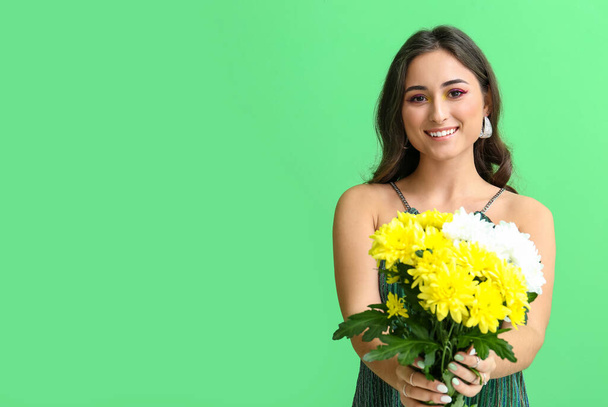 緑の背景に花の花束を保持した創造的な化粧で笑顔の女性。国際女性デー - 写真・画像