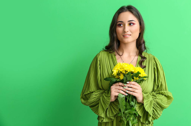 Mujer de moda con maquillaje creativo que sostiene ramo de flores sobre fondo verde. Día Internacional de la Mujer - Foto, Imagen