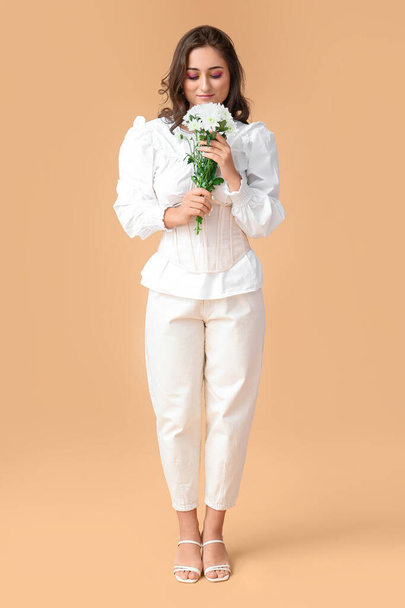 色の背景に花の花束を保持するファッショナブルな女性。国際女性デー - 写真・画像
