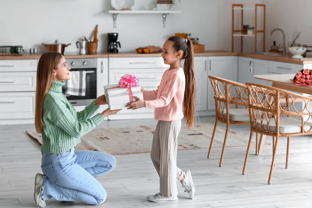 Little girl greeting her mother with present in kitchen on International Women's Day - Photo, Image