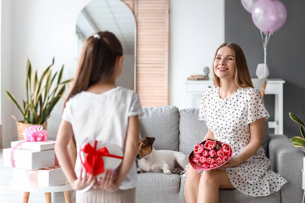 Gelukkige moeder met boeket tulpen en haar dochtertje thuis op Internationale Vrouwendag - Foto, afbeelding
