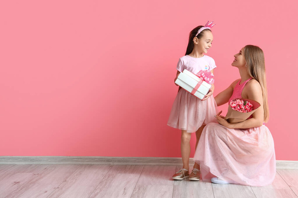 ピンクの壁の近くに母親と贈り物を持つ少女。国際女性デーのお祝い - 写真・画像