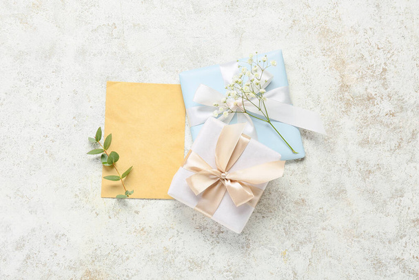 Blanco wenskaart voor Internationale Vrouwendag, geschenkdozen, eucalyptustak en gipskruid bloemen op grunge achtergrond - Foto, afbeelding
