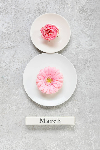 Kreatywna kompozycja z talerzami, kwiatami i słowem Marsz na jasnym tle. Międzynarodowy Dzień Kobiet - Zdjęcie, obraz