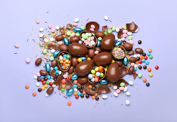 キャンディと紫の背景にスプリンクル付きチョコレートイースターエッグ - 写真・画像