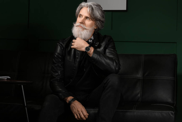 Portrait of handsome mature bearded man sitting on sofa at home - Фото, зображення