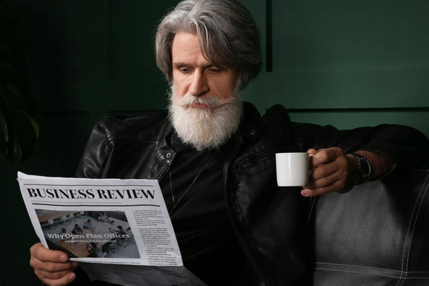 Przystojny, dojrzały brodaty mężczyzna pijący kawę i czytający gazety w domu - Zdjęcie, obraz