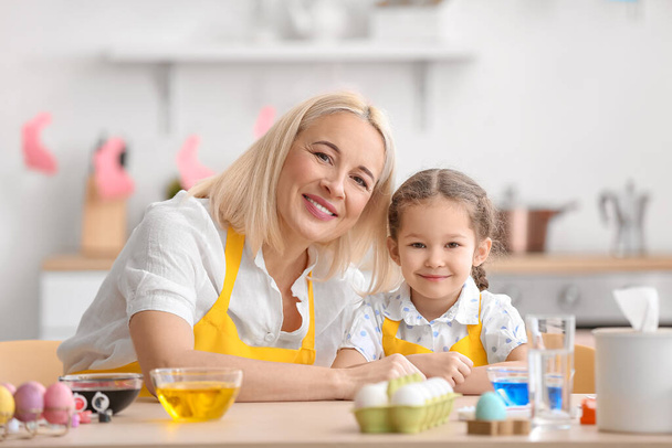 Little girl and her grandmother painting Easter eggs at home - Foto, Bild