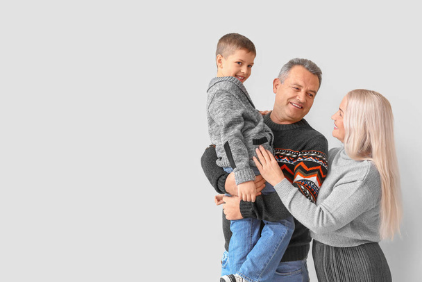 Kleiner Junge mit seinen Großeltern in warmen Pullovern vor hellem Hintergrund - Foto, Bild