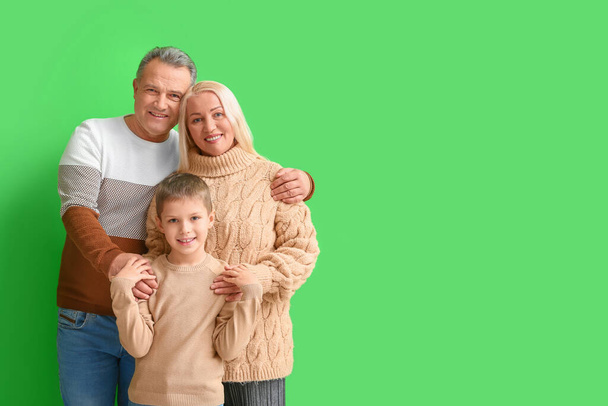 Petit garçon avec ses grands-parents dans des pulls chauds étreignant sur fond vert - Photo, image