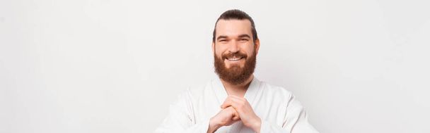 Portrait of cheerful bearded man saluting and wearing dobok - Photo, image
