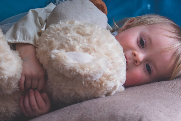 Μικρό χαριτωμένο κοριτσάκι με αρκουδάκι πριν τον ύπνο. - Φωτογραφία, εικόνα