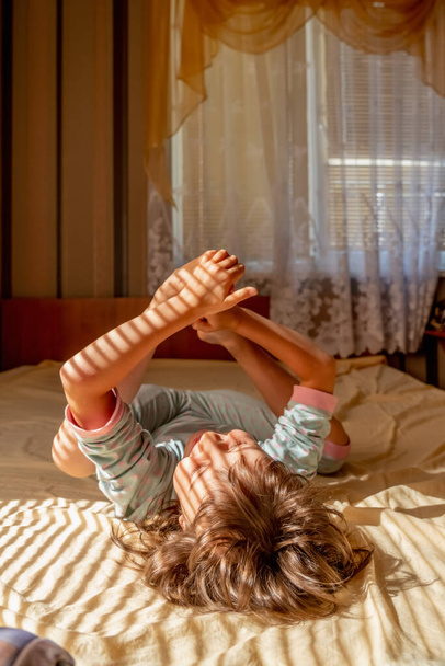 image of  happy  beautiful girl in pajamas lying upside down and gwaking up in the sunny morning.  - Foto, Imagen