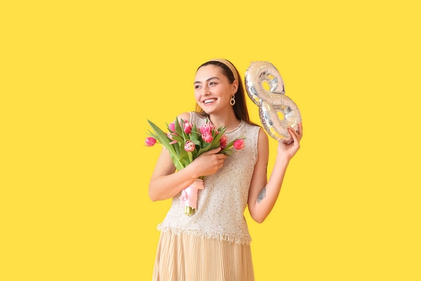 Happy young woman with bouquet and balloon in shape of figure 8 on yellow background. International Women's Day - Photo, image