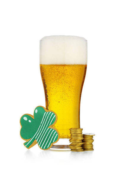 Склянка пива, пряничне печиво та монети на честь Дня Святого Патрика на білому тлі. - Фото, зображення