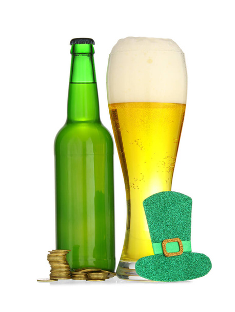 Бутылка и стакан пива с монетами для празднования Дня Святого Патрика на белом фоне - Фото, изображение