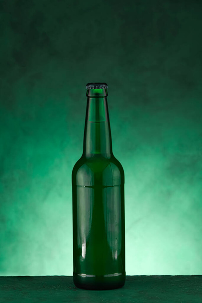 Bottle of beer for St. Patrick's Day celebration on green background - Фото, изображение
