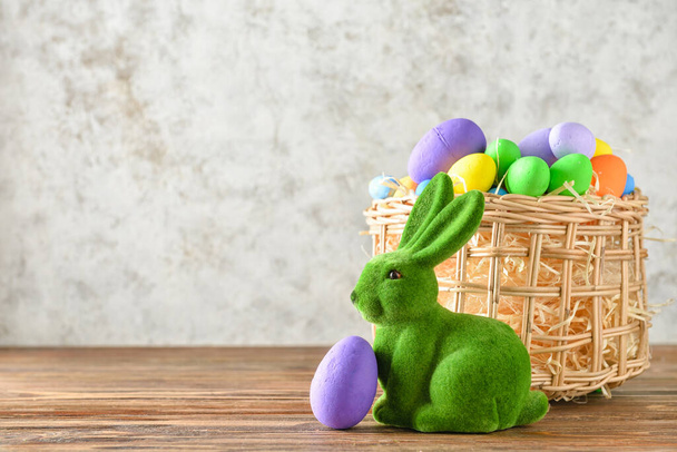 Paskalya tavşanı ve hasır sepeti, arka planda boyanmış yumurtalar. - Fotoğraf, Görsel
