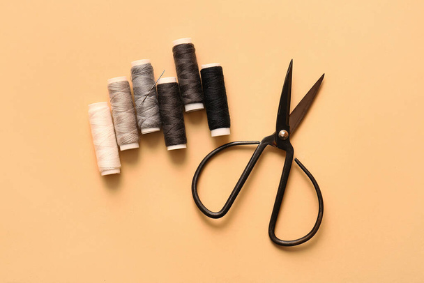 Thread spools and scissors on color background - Фото, изображение