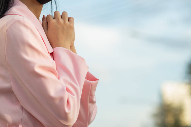 Uma menina vestindo um casaco rosa está de pé orando a Deus pedindo a bênção de Deus para trazer seu amante de volta para ela. conceito de crer e o poder da fé em Deus e bênçãos - Foto, Imagem