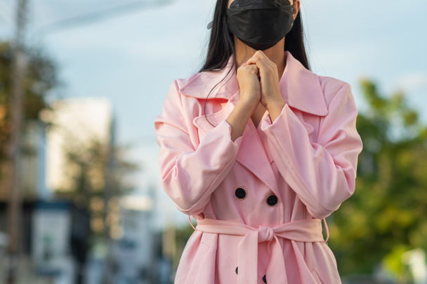 Ein Mädchen in einem rosafarbenen Mantel steht und betet zu Gott und bittet um Gottes Segen, ihren Liebhaber zu ihr zurückzubringen. Konzept des Glaubens und der Kraft des Glaubens an Gott und Segen - Foto, Bild