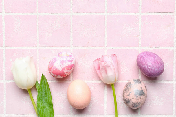 Composition avec de beaux œufs de Pâques et des fleurs de tulipe sur la tuile de couleur - Photo, image