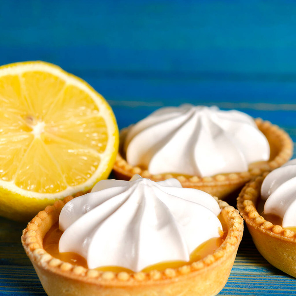 Tartaletas de limón, mini tarta casera de pan corto con cuajada de limón y crema batida, espacio de copia de fondo azul - Foto, imagen