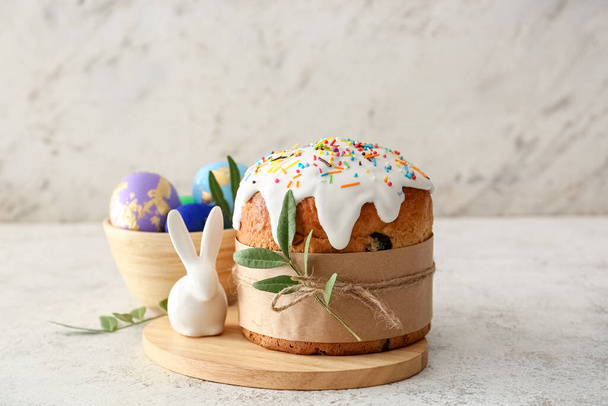 Dřevěná deska s lahodnými velikonoční dort a vejce na světlém pozadí - Fotografie, Obrázek