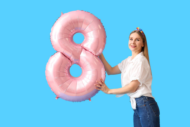 Beautiful woman with big balloon in shape of figure 8 on blue background. International Women's Day - Photo, Image