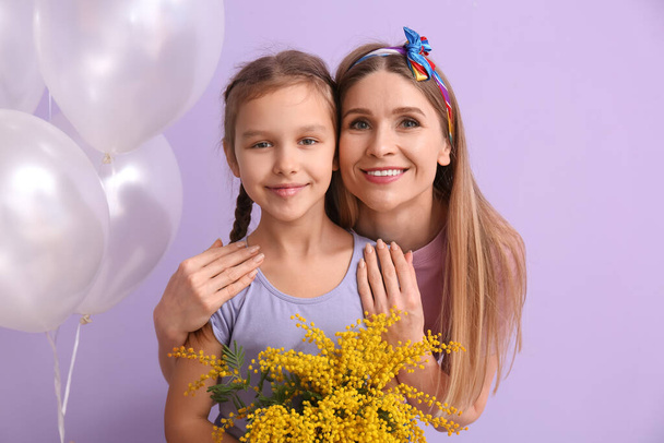 Niña, su madre con flores y globos sobre fondo lila - Foto, imagen