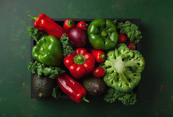 assorted red and green vegetables tomatoes, bell peppers, kale avocado in wooden tray - 写真・画像