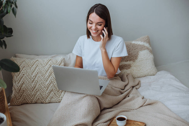 Young woman working on laptop at home in bed - Foto, Bild
