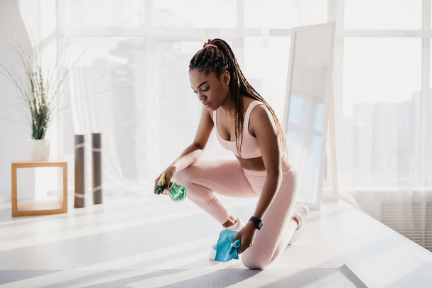 Millennial African American kobieta w odzieży sportowej wycieranie maty do jogi po treningu w domu siłowni, puste miejsce - Zdjęcie, obraz