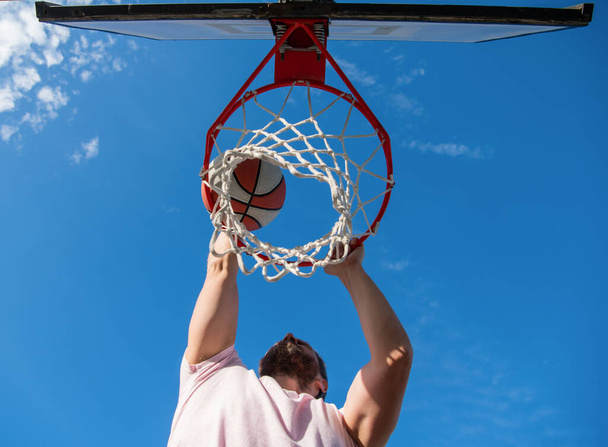 young man with basketball ball on court. professional basketball player training outdoor. - 写真・画像