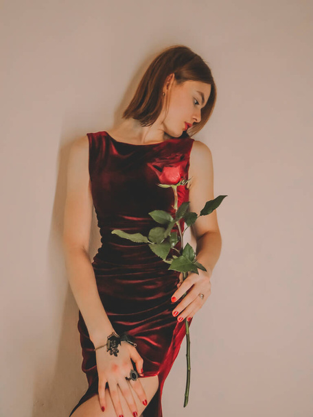 Portrait of a beautiful young woman with a red rose, the concept of holidays, March 8, romantic dates and meetings, gifts to beloved women, Valentine's day - 写真・画像