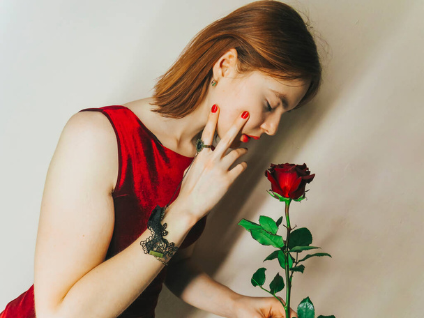 Portrait of a beautiful young woman with a red rose, the concept of holidays, March 8, romantic dates and meetings, gifts to beloved women, Valentine's day - Foto, imagen