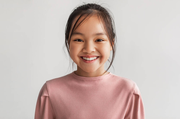 Headshot Of Toothy Chinese Kid Girl Posing Smiling, Gray Background - Фото, изображение