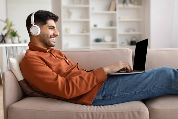 Портрет улыбающегося арабского мужчины, использующего компьютер дома - Фото, изображение