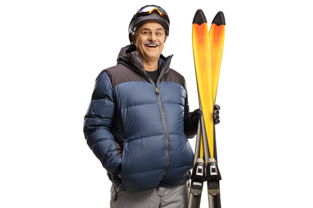 Mature man holding a pair of skis isolated on a white background - Valokuva, kuva