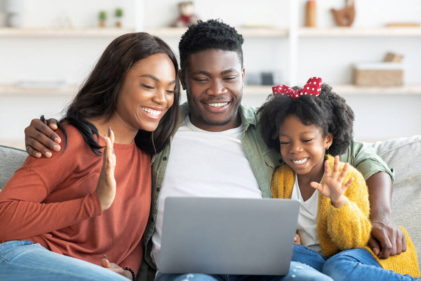Felice famiglia nera di tre fare videochiamata con il computer portatile a casa - Foto, immagini
