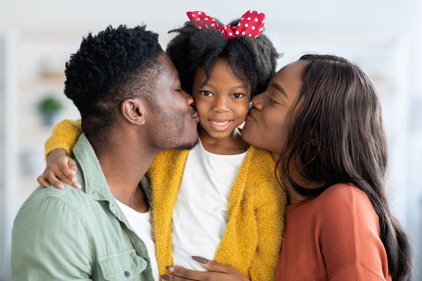 Amar a la familia. feliz africano americano padres besos su lindo poco hija - Foto, Imagen