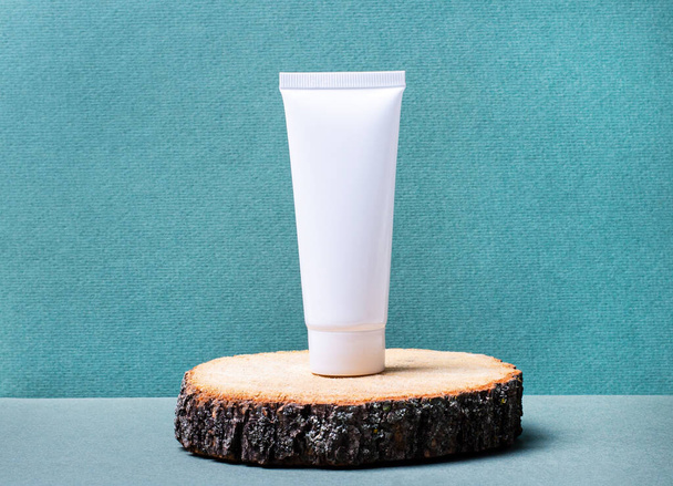 A white tube for cream stands on a podium made of natural wood. Ecological concept. Place to insert text. Mockup. Place to copy. - Foto, Imagen