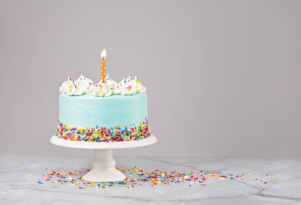 Blauwe verjaardagstaart met hagelslag en verjaardagskaars - Foto, afbeelding