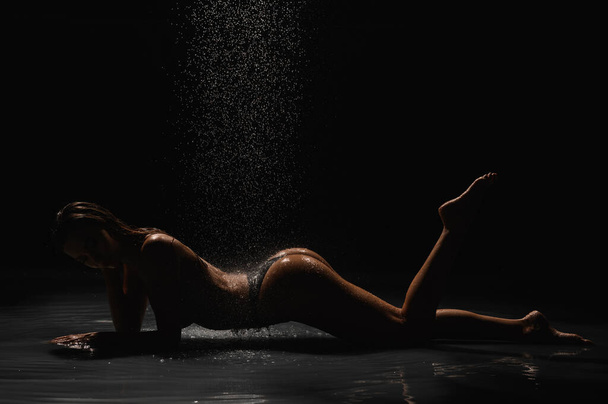 Lány gyönyörű alakkal egy fekete ciklámán a zuhany alatt - Fotó, kép
