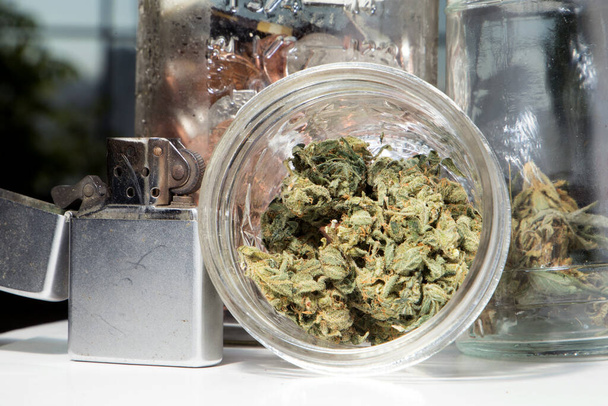 Marijuana and Cannabis Bud in Jar and  cigarette lighter - Photo, image