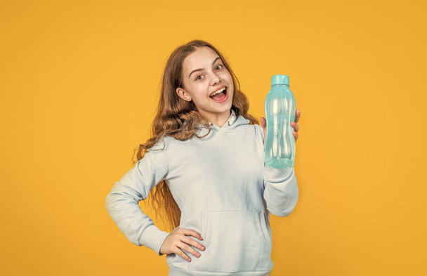 happy smiling kid girl hold water bottle for drinking after sport workout, thirsty - Fotó, kép