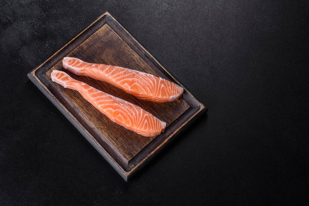 Du saumon. Filet de saumon cru frais avec des ingrédients de cuisson et des herbes sur fond noir - Photo, image
