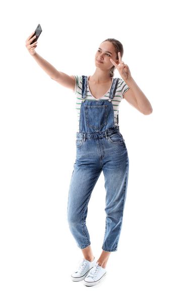 Junge Frau im Jeansanzug macht Selfie auf weißem Hintergrund - Foto, Bild