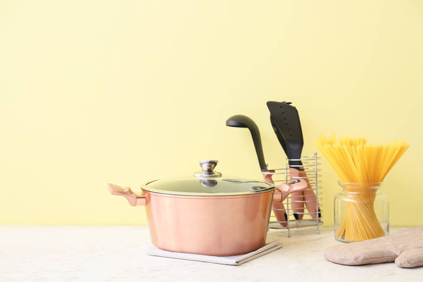 Utensilios de cocina de cobre y frasco con pasta cruda sobre la mesa sobre fondo amarillo - Foto, imagen