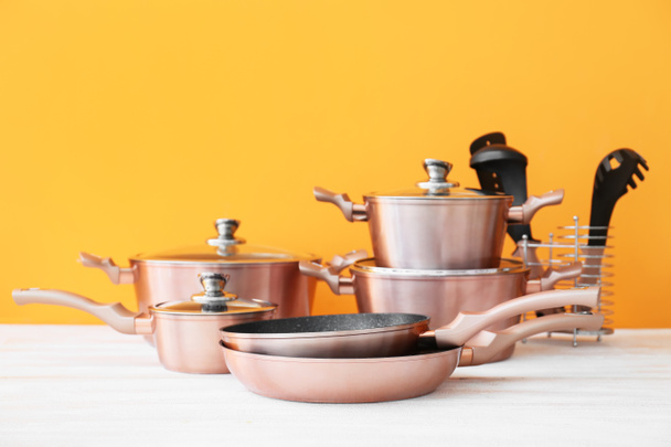 Conjunto de utensílios de cozinha de cobre sobre mesa de madeira branca contra fundo laranja - Foto, Imagem